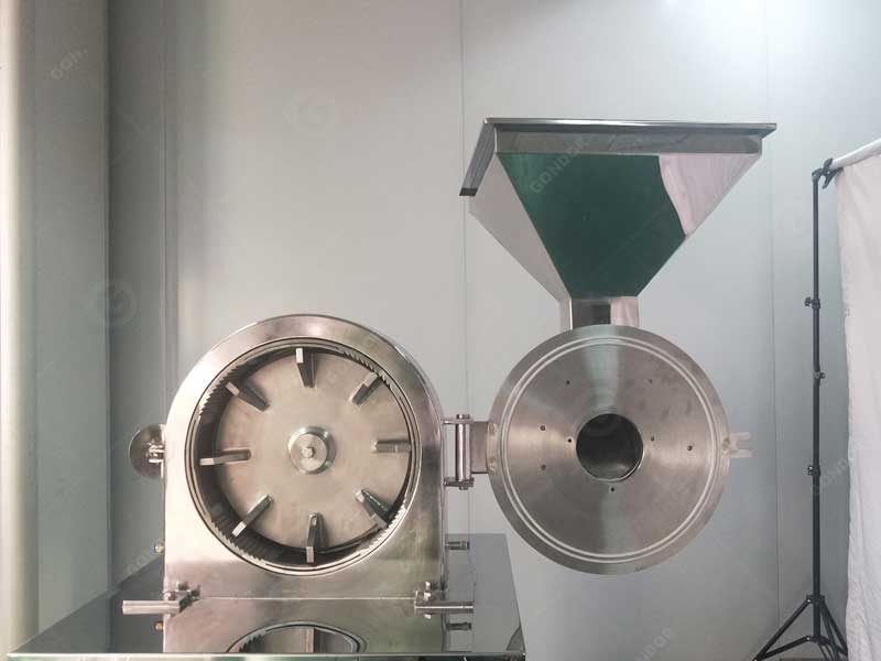 Open cocoa powder grinder chamber showing hinged door and grinding elements
