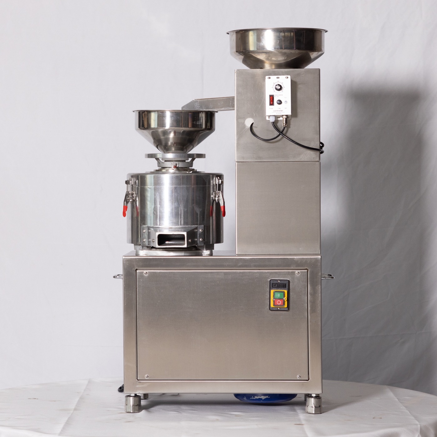 Automatic oil press feeder with stainless steel bowl hopper and speed control box, mounted above a clarifier drum